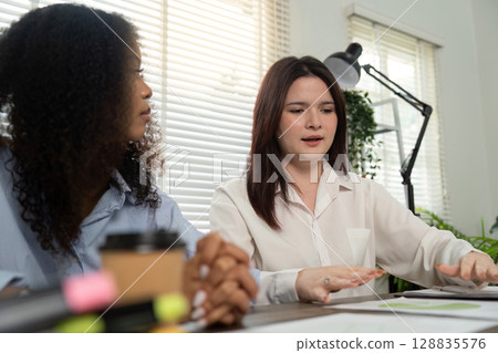Professional Interaction. Woman explaining concepts to her colleague in a bright office. Professional Interaction. Woman explaining concepts to her colleague in a bright office. 128835576