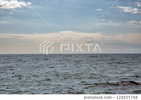 Calm sea horizon under cloudy blue sky 128835788
