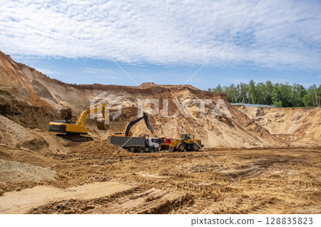 The process of loading sand in a sand quarry. Trucks are waiting for cargo. 128835823