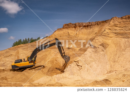A caterpillar tractor works with a bucket in a sand pit. Sand mining 128835824