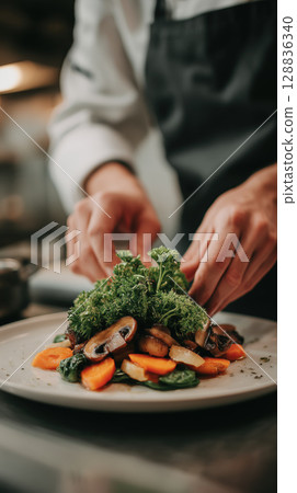 Chef artfully arranges vibrant plant based dish with fresh vegetables and herbs, showcasing culinary creativity 128836340