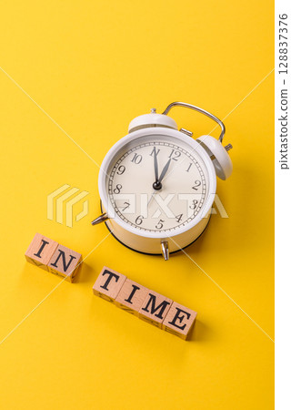 Vintage alarm clock with time or on time inscription on yellow background 128837376