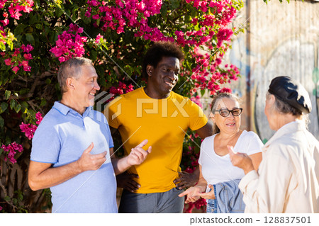 Mature multinational cheerful males and females talking outdoors near the park on a sunny day 128837501