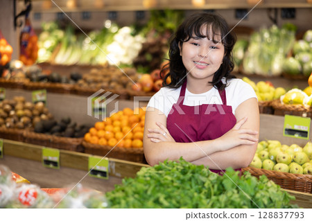 Portrait of friendly smiling female employee of grocery supermarket with parsley Portrait of friendly smiling female employee of grocery supermarket with parsley 128837793