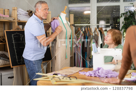 Sewing school senior man teacher conducts lesson for elderly students, using mannequin 128837798