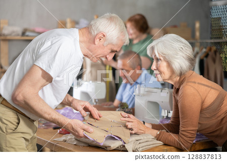 Woman discussing pattern with classmate during sewing course for older adults 128837813