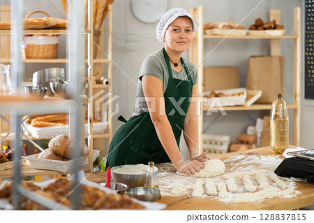 Woman works in bakery as baker, kneads dough, works with flour. Woman works in bakery as baker, kneads dough, works with flour. 128837815