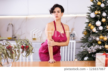 Seductive shorthaired woman dressed only in apron standing near table Seductive shorthaired woman dressed only in apron standing near table 128837867