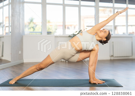 Lover of active lifestyle on yoga mat perform doing Utthita Parshvakonasana in gym Lover of active lifestyle on yoga mat perform doing Utthita Parshvakonasana in gym 128838061