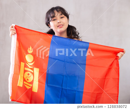 Smiling young girl holding flag of Mongolia 128838072