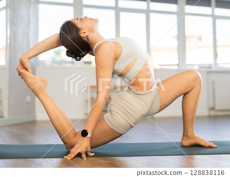 Lover of active lifestyle on yoga mat perform doing Anjaneyasana in gym Lover of active lifestyle on yoga mat perform doing Anjaneyasana in gym 128838116