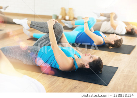 Girl doing glutes stretching exercises during training in gym Girl doing glutes stretching exercises during training in gym 128838134