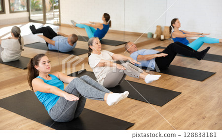 Group of young senior old people in active wear pushing press on mats during Pilates class together in studio 128838181
