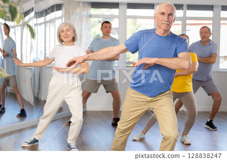 Woman participating in Zumba class for seniors in fitness studio 128838247