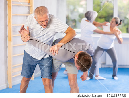 Old man twisting her opponent's arm during self-defense classes Old man twisting her opponent's arm during self-defense classes 128838288