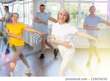 Woman participating in Zumba class for seniors in fitness studio Woman participating in Zumba class for seniors in fitness studio 128838292
