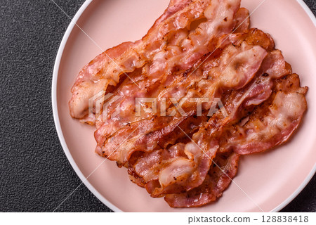 Cooked crispy bacon, slices of roast pork for an English breakfast. Fried bacon Cooked crispy bacon, slices of roast pork for an English breakfast. Fried bacon 128838418