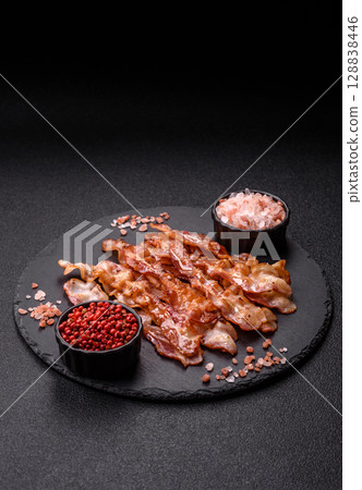 Cooked crispy bacon, slices of roast pork for an English breakfast. Fried bacon Cooked crispy bacon, slices of roast pork for an English breakfast. Fried bacon 128838446