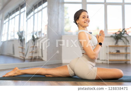Lover of active lifestyle on yoga mat perform doing Eka Pada Rajakapotasana in gym 128838471