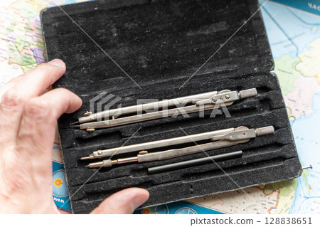 Cartographer holding drafting compass case over map 128838651