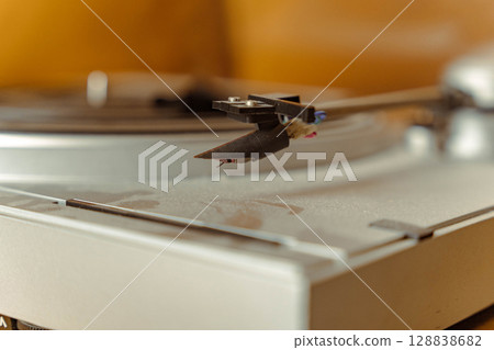 Close-up of a turntable needle cartridge playing a vinyl record, evoking nostalgia and the warm sound of analog music Close-up of a turntable needle cartridge playing a vinyl record, evoking nostalgia and the warm sound of analog music 128838682