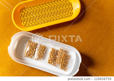 Wheatgrass growing kit with seeds and yellow strainer on orange background Wheatgrass growing kit with seeds and yellow strainer on orange background 128838759