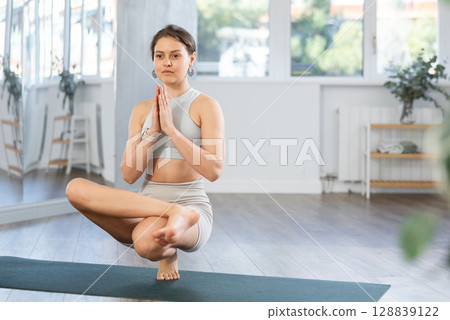 Sporty young woman performing advanced yoga posture in studio Sporty young woman performing advanced yoga posture in studio 128839122