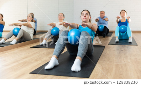 Young girl doing sit-ups with bender ball in pilates studio 128839230
