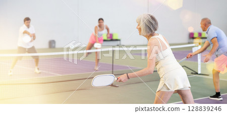 Sportive slim woman with racquet playing pickleball in court. View from back 128839246