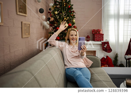 Joyful moments shared during a festive video call in a cozy living room adorned for the holiday season 128839396