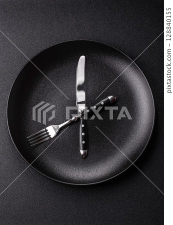 Empty plate with devices in the form of clock hands as a conceptual background for lunch time 128840155