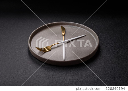 Empty plate with devices in the form of clock hands as a conceptual background for lunch time Empty plate with devices in the form of clock hands as a conceptual background for lunch time 128840194