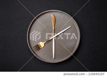 Empty plate with devices in the form of clock hands as a conceptual background for lunch time Empty plate with devices in the form of clock hands as a conceptual background for lunch time 128840197