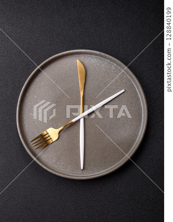 Empty plate with devices in the form of clock hands as a conceptual background for lunch time Empty plate with devices in the form of clock hands as a conceptual background for lunch time 128840199