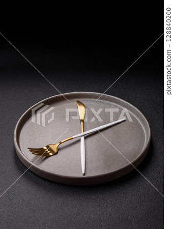 Empty plate with devices in the form of clock hands as a conceptual background for lunch time 128840200