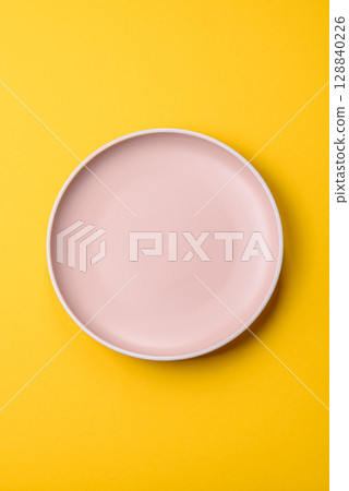 Empty round ceramic plate on yellow background. Food background Empty round ceramic plate on yellow background. Food background 128840226