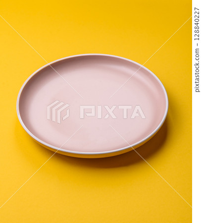 Empty round ceramic plate on yellow background. Food background 128840227