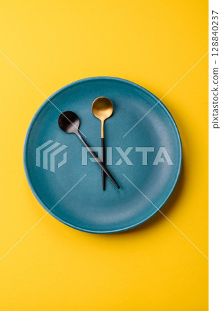 Empty plate with devices in the form of clock hands as a conceptual background for lunch time Empty plate with devices in the form of clock hands as a conceptual background for lunch time 128840237