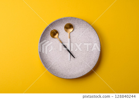 Empty plate with devices in the form of clock hands as a conceptual background for lunch time 128840244