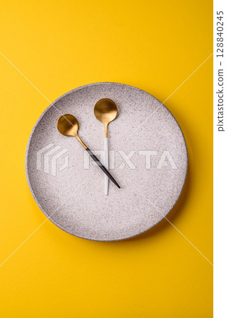 Empty plate with devices in the form of clock hands as a conceptual background for lunch time 128840245