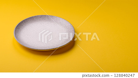 Empty round ceramic plate on yellow background. Food background Empty round ceramic plate on yellow background. Food background 128840247