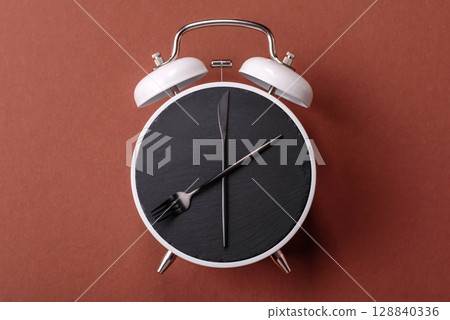Empty plate with devices in the form of clock hands as a conceptual background for lunch time Empty plate with devices in the form of clock hands as a conceptual background for lunch time 128840336