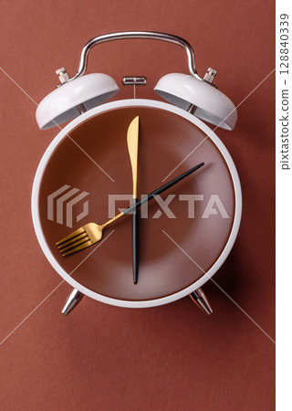 Empty plate with devices in the form of clock hands as a conceptual background for lunch time Empty plate with devices in the form of clock hands as a conceptual background for lunch time 128840339