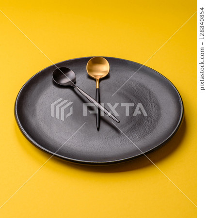 Empty plate with devices in the form of clock hands as a conceptual background for lunch time 128840854