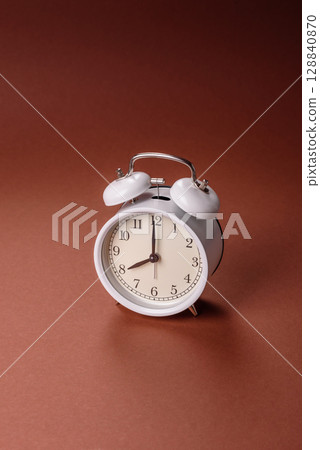Vintage alarm clock on brown surface as a conceptual background for deadlines for tasks 128840870