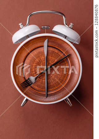 Empty plate with devices in the form of clock hands as a conceptual background for lunch time Empty plate with devices in the form of clock hands as a conceptual background for lunch time 128840876