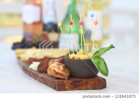 Italian charcuterie board featuring crackers cheese and salami served on wooden plank with raw bark edge Italian charcuterie board featuring crackers cheese and salami served on wooden plank with raw bark edge 128841073