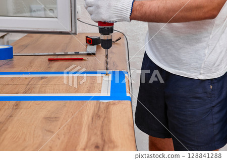repairman using electric drill and installation new modern kitchen 128841288