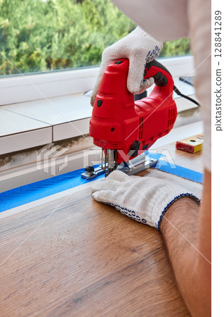 repairman using electric jigsaw and cutting hole for the sink in the kitchen countertops, Woodworking and carpentry concept repairman using electric jigsaw and cutting hole for the sink in the kitchen countertops, Woodworking and carpentry concept 128841289