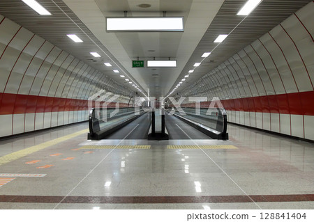 moving escalator in subway station. Walkway with Blank billboard located in underground hall or subway for advertising, mockup concept, 128841404